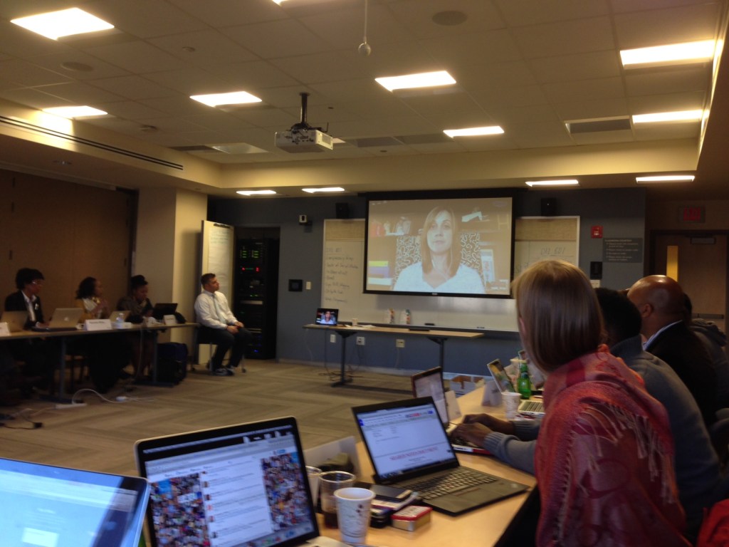 Graduate students zooming with a guest speaker in a college classroom.