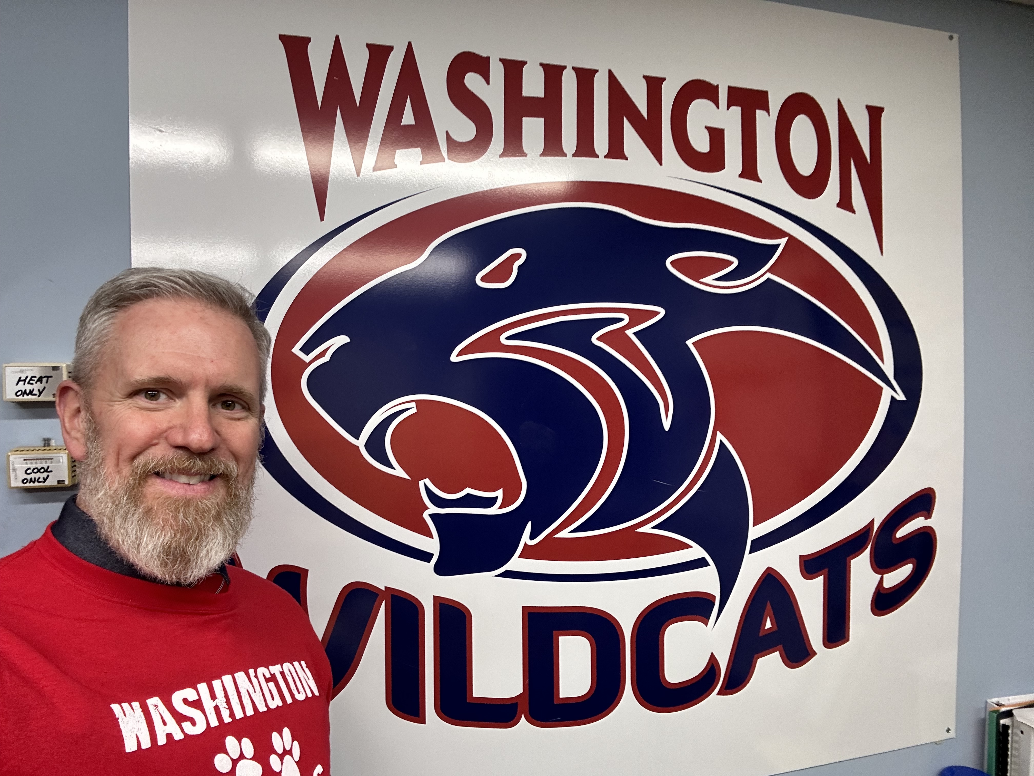 Roth standing in front of Washington Wildcats banner.